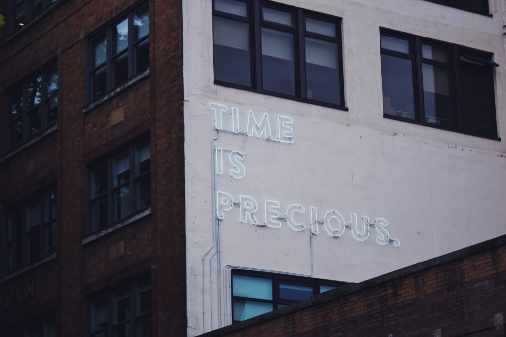 TIME IS PRECIOUS neon sign on an office building
